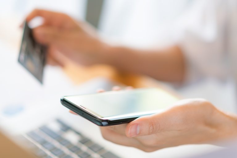 hands holding a credit card using laptop computer and mobile pho