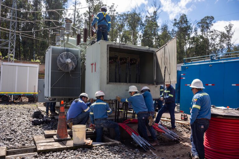 Trabajadores de mantenimiento eléctrico realizan tareas de conexión de cables de alta tensión en un transformador de potencia en una subestación eléctrica.