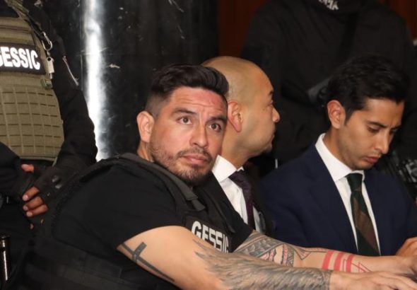 Daniel Salcedo, sentado junto a agentes de seguridad, en una imagen de archivo.