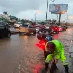 Un agente de ATM despeja una alcantarilla en una avenida inundada de Guayaquil, el 19 de octubre de 2026.
