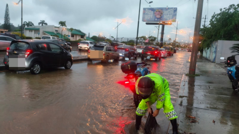 Un agente de ATM despeja una alcantarilla en una avenida inundada de Guayaquil, el 19 de octubre de 2026.
